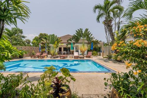 una piscina con palmeras y una casa en Baan Coconut en Bang Tao Beach