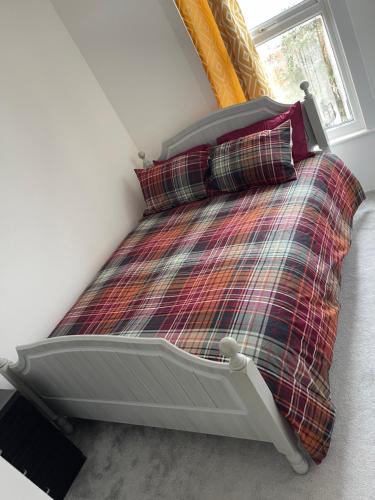 a bedroom with a bed with a plaid blanket and a window at Evanelly lodge in Gillingham