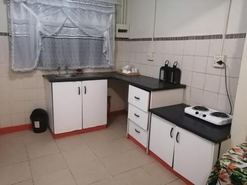 eine Küche mit weißen Schränken und einer schwarzen Arbeitsplatte in der Unterkunft Limelight in Polokwane