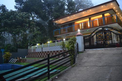 a house with a fence in front of it at Arabian Nights Munnar Pool Villa in Munnar