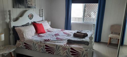 a bedroom with a white bed with a red pillow at CHURCHILL COTTAGE- 94 Churchill St Maryborough QLD in Maryborough