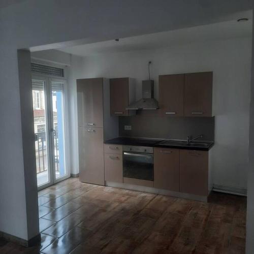 une cuisine vide avec du parquet et une cuisine avec une cuisinière dans l'établissement F2 Mass & Bo, à Thaon-les-Vosges