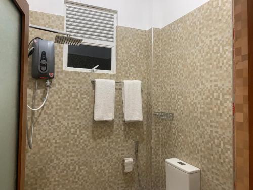 a bathroom with a shower with a toilet and a window at Imperial Resort in Udawalawe