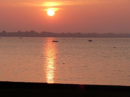 a sunset over a large body of water with boats at Maison front de mer in Damgan