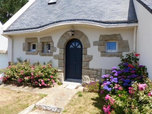 a white house with a black door and some flowers at Maison front de mer in Damgan