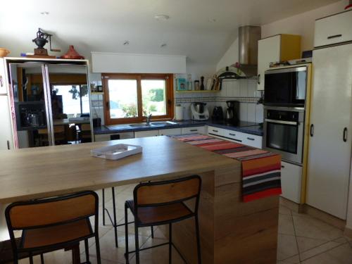 a kitchen with a large wooden island with bar chairs at Maison front de mer in Damgan