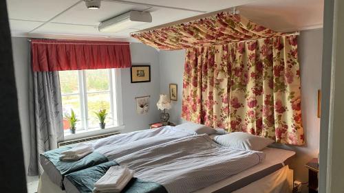 Schlafzimmer mit einem Bett und einem Fenster mit Vorhängen in der Unterkunft Björsjöås Vildmark - room in the main house in Olofstorp