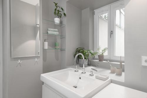 a white bathroom with a sink and a window at Exklusiv: Historisches Apartment mit Deckengewölbe in Munich