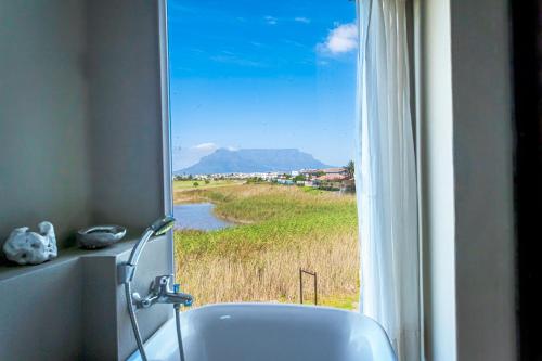 a bathroom with a tub and a window with a view at Gaia Hydro-Spa and Guest House in Cape Town