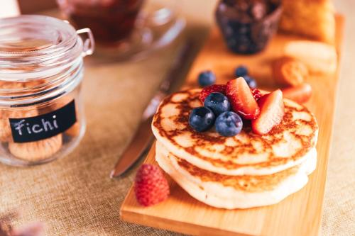 a stack of pancakes with fruit on a cutting board at Camino Rustic Chic Hotel in Livigno