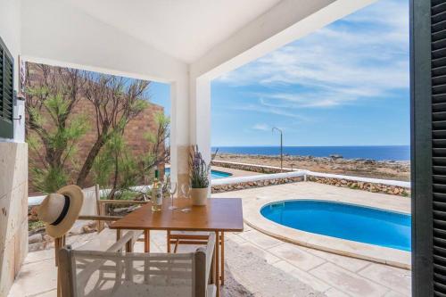 une terrasse avec une table et une piscine dans l'établissement Sa Calma, à Cala Blanca