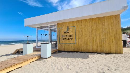 a building on the beach with a beach survey sign on it at Wave by Baltic Home in Międzyzdroje