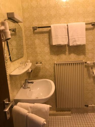 a bathroom with a sink and a mirror and towels at Gasthof und Pension Zur Frischen Quelle in Heigenbrücken