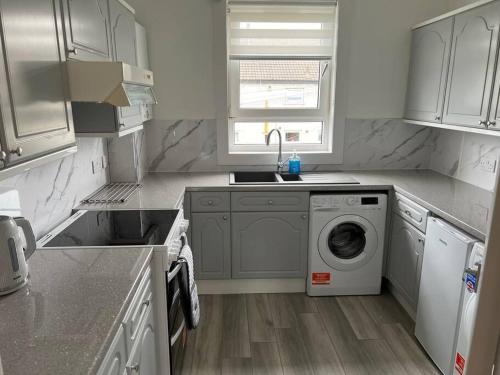 a kitchen with a washing machine and a sink at Cosy Cottage Apartment in Helensburgh