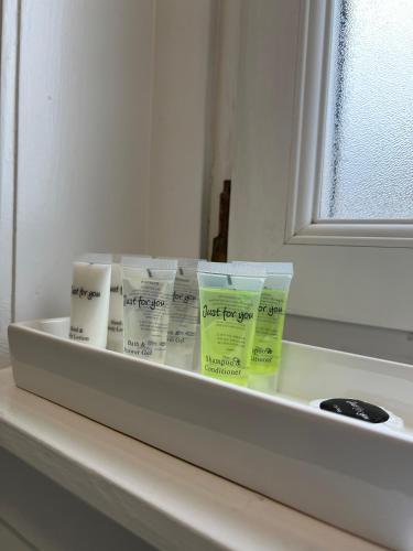 a shelf with four bottles of toothpaste and a mirror at Cosy Cottage Apartment in Helensburgh