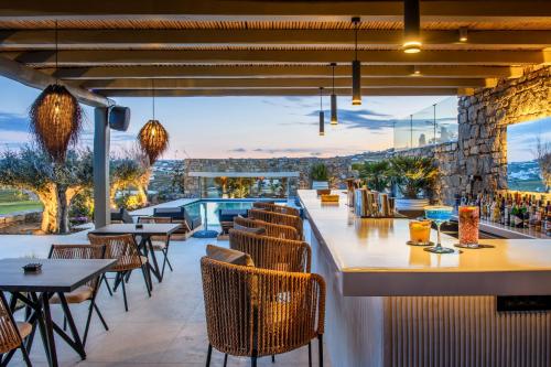 a restaurant with a view of a pool and tables and chairs at Nasta Suites & Villas Intentional Living Mykonos in Mikonos