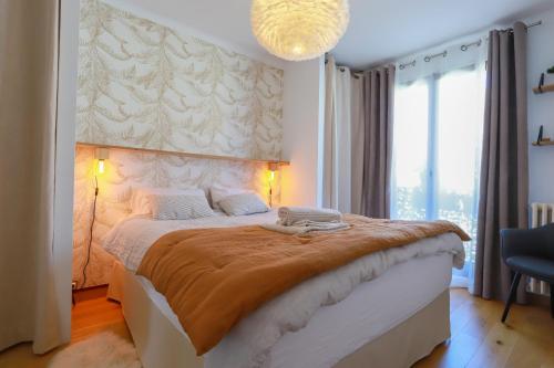 Un dormitorio con una cama grande y una lámpara de araña. en Manoir 4 étoiles - 2 chambres, proche lac, en Annecy