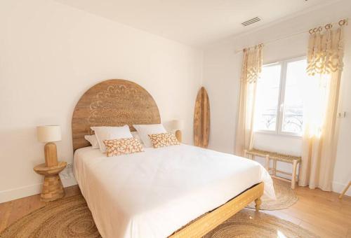 Schlafzimmer mit einem großen weißen Bett und einem großen Fenster in der Unterkunft Bornéo du Château Saint-Laurent in Saint-Laurent-de-Médoc