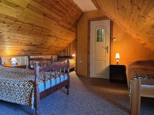 a bedroom with two beds and a wooden ceiling at Zubrowa Ostoja 