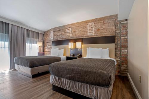 Best Western Plus St. Christopher Hotel في نيو أورلينز: غرفة فندقية بسريرين وجدار من الطوب