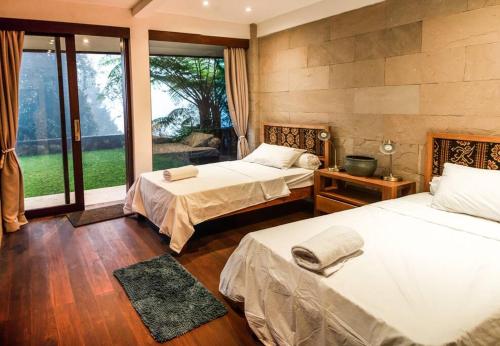 a bedroom with two beds and a large window at Villa Jado 3 - Lake and Mountain View Villa in Bedugul