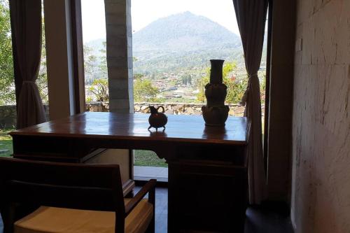 a table with a vase and a cat sitting on it at Villa Jado 3 - Lake and Mountain View Villa in Bedugul
