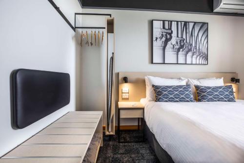 a bedroom with a bed and a flat screen tv at Nightcap at Empire Hotel in Gepps Cross