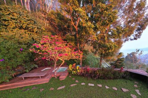 a garden with a bench and a tree with pink flowers at Villa Jado 3 - Lake and Mountain View Villa in Bedugul