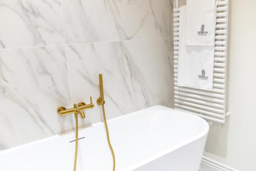 a bathroom with a white tub and a toilet at Srebrna Luxury Apartments - willa fabrykancka - wnętrza premium in Łódź