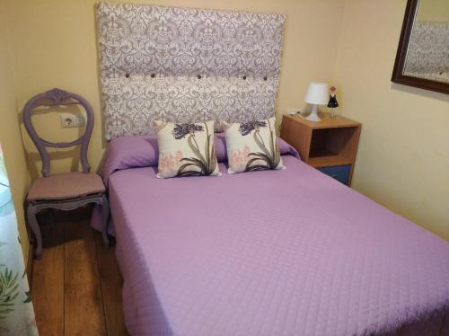 a bedroom with a purple bed and a chair at Casita con terreno a 10 minutos del centro de Vigo in Moaña