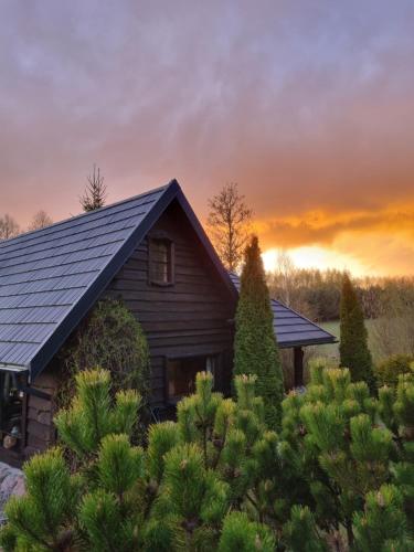a house with a group of trees in front of a sunset at Wiejska Chata in Barczewo