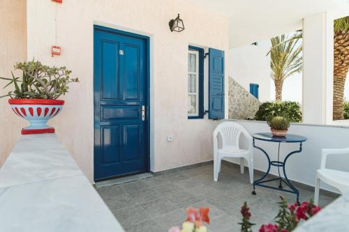 a blue door on a patio with a table and chairs at Villa Limnes in Perissa