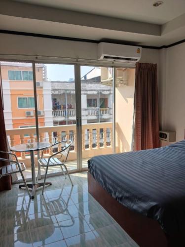 1 dormitorio con cama, mesa y balcón en Kalisa House@Soi welcome en Jomtien Beach