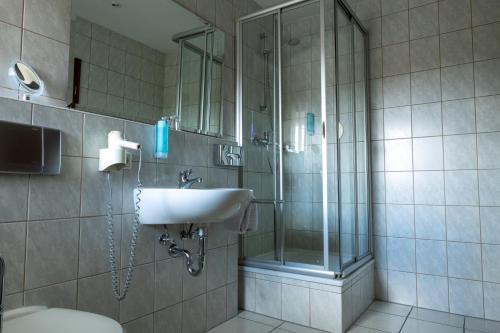 a bathroom with a glass shower and a sink at Hotel Anker in Saalfeld