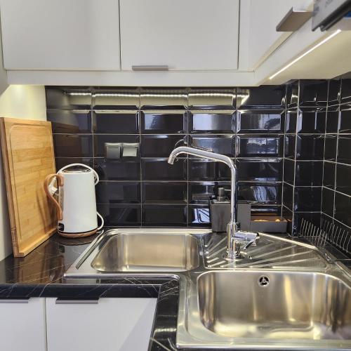 a kitchen with a stainless steel sink and black tiles at Karystos sea side apartment in Karistos