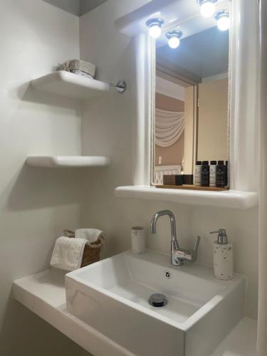 a white bathroom with a sink and a mirror at Aggelos Studios in Adamas