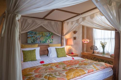 une chambre avec un lit à baldaquin avec des oreillers verts dans l'établissement Chalet Rabina, à Ubud
