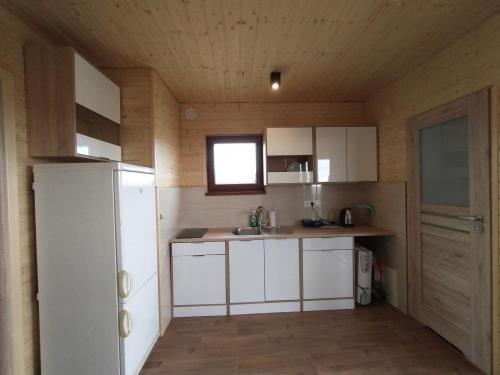 a small kitchen with white cabinets and a window at Domek na wyłączność LAWENDA in Jezierzany