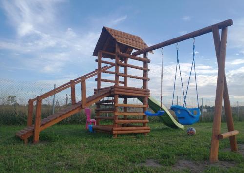 a wooden playground with a slide and swings at Domek na wyłączność LAWENDA in Jezierzany