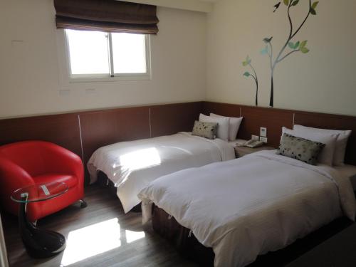a hotel room with two beds and a red chair at Royal Hotel in Magong
