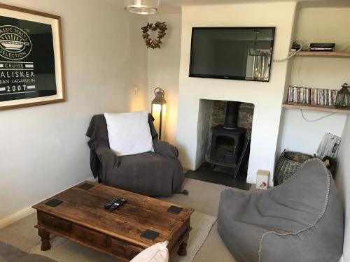 un soggiorno con un divano, un tavolo e una TV di Cosy Cottage in Lovely Georgeham a Georgeham