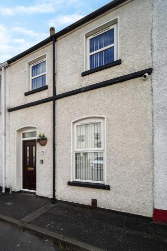 a white brick house with two windows and a door at Carlisle Lodge 'Sleeping 6 guests' in Derry Londonderry
