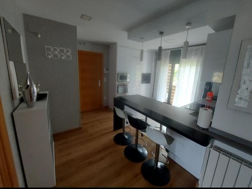 cocina con encimera negra y 2 taburetes en Alojamientos Marte apartamento a pie de playa y garaje, en Suances
