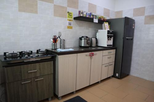 a kitchen with a stove and a refrigerator at Dudu Guesthouse Kuala Kangsar in Kuala Kangsar