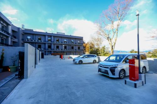 two cars parked in a parking lot in front of a building at Dormy Inn Express Fujisan Gotemba in Gotemba