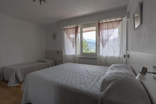 1 dormitorio con 2 camas y ventana en Vue sur les montagnes, en Embrun