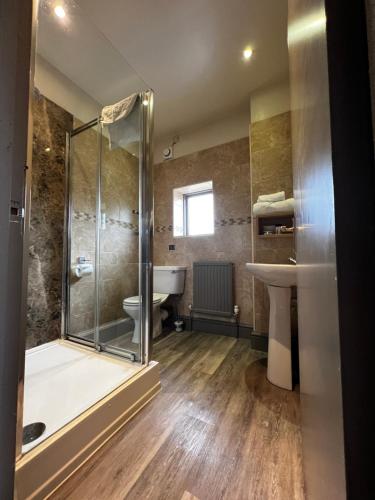 uma casa de banho com um chuveiro, um WC e um lavatório. em Herriots Hotel em Skipton