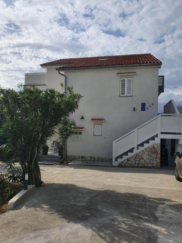a large white house with a car parked in front of it at 6 M, 50 m do plaže in Barbat na Rabu