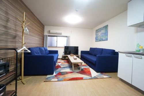 a living room with blue couches and a table at Family Home Rinka Shitennoji RKA in Osaka