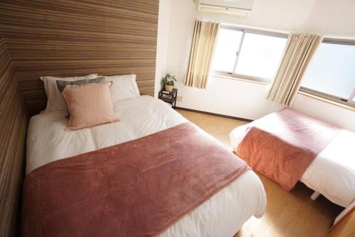 a bedroom with two beds and a window at Family Home Rinka Shitennoji RKA in Osaka